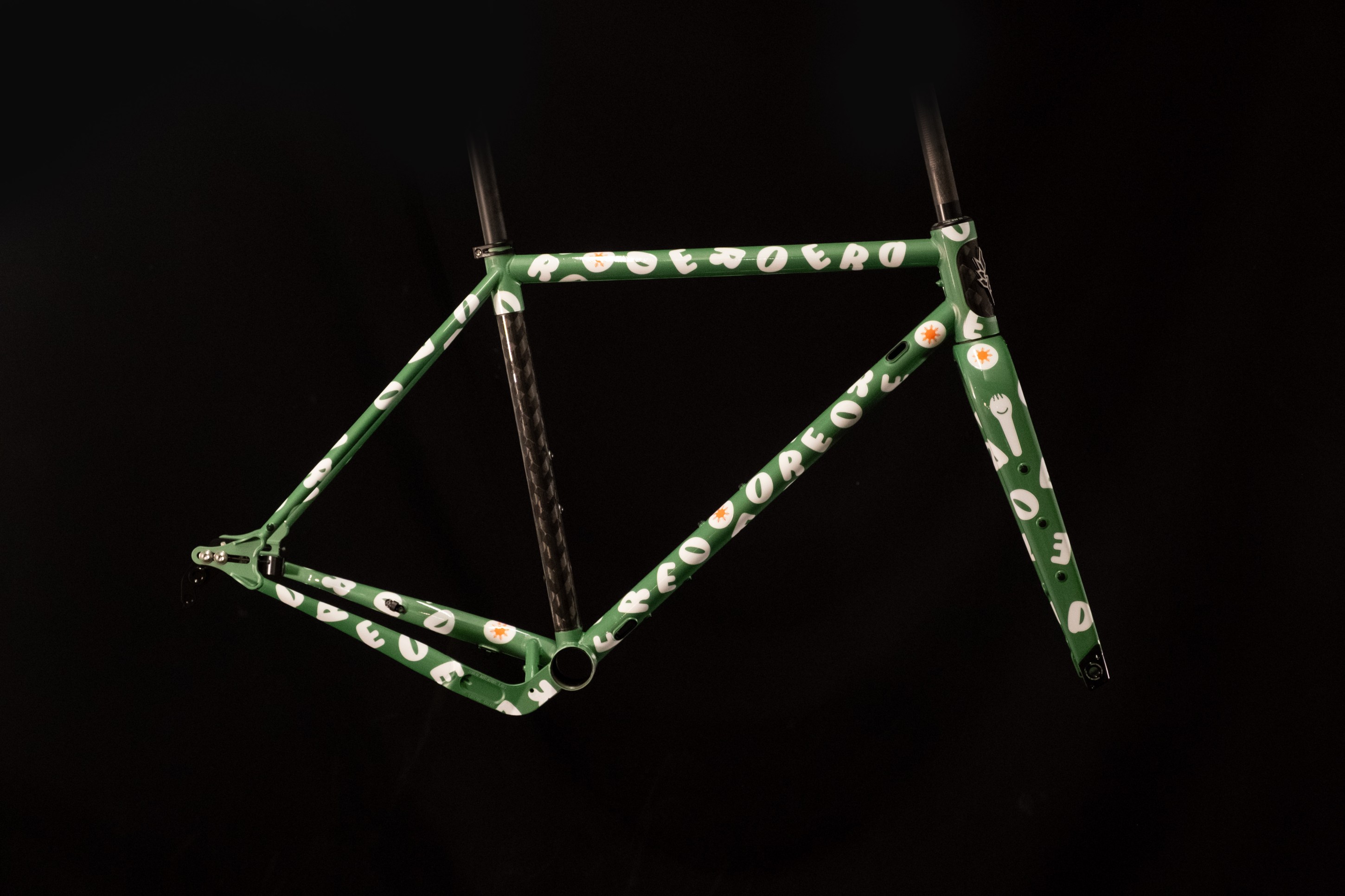 A green bicycle frame with playful, white graphic letters and designs, displayed against a black background.