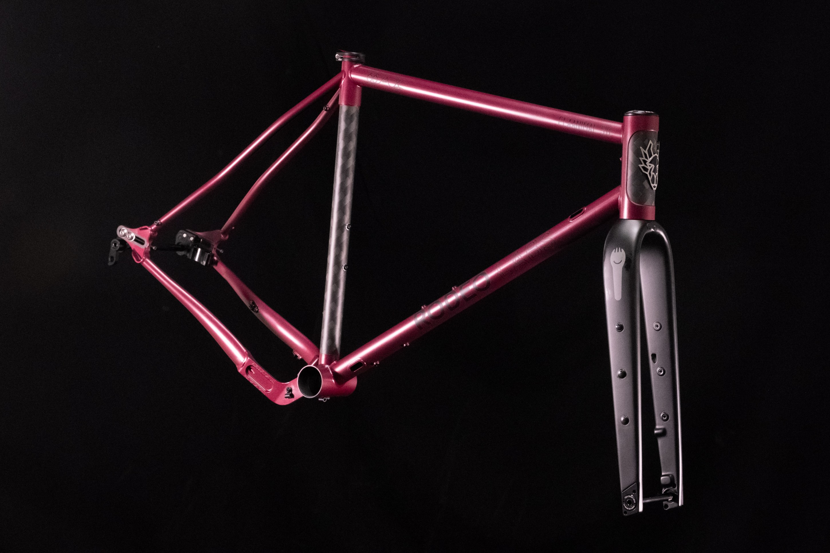 A pink bicycle frame displayed against a black background.