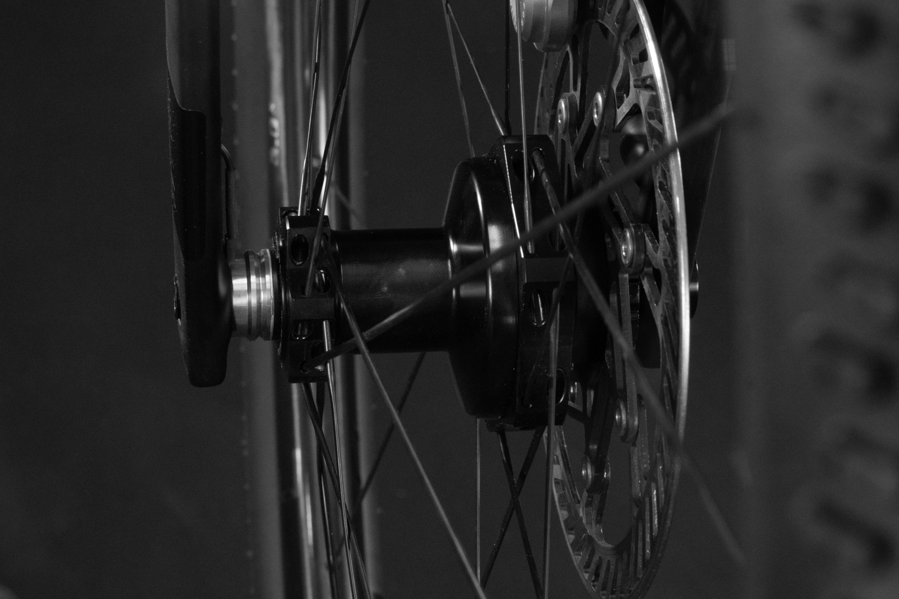 Close-up of a bicycle wheel hub and disc brake in black and white.