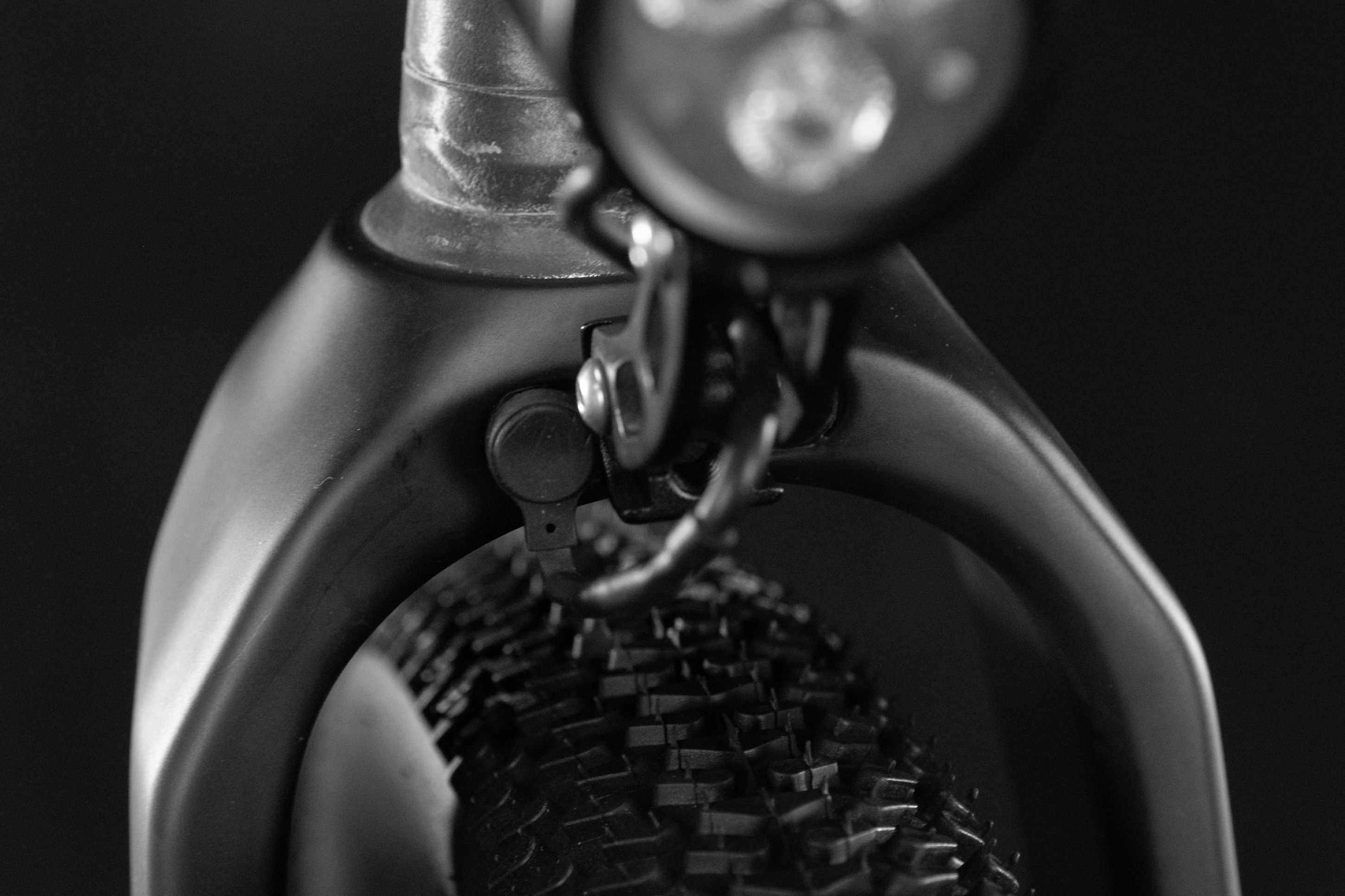 Close-up of a bicycle's front fork and tire, featuring a light and a cable connection.