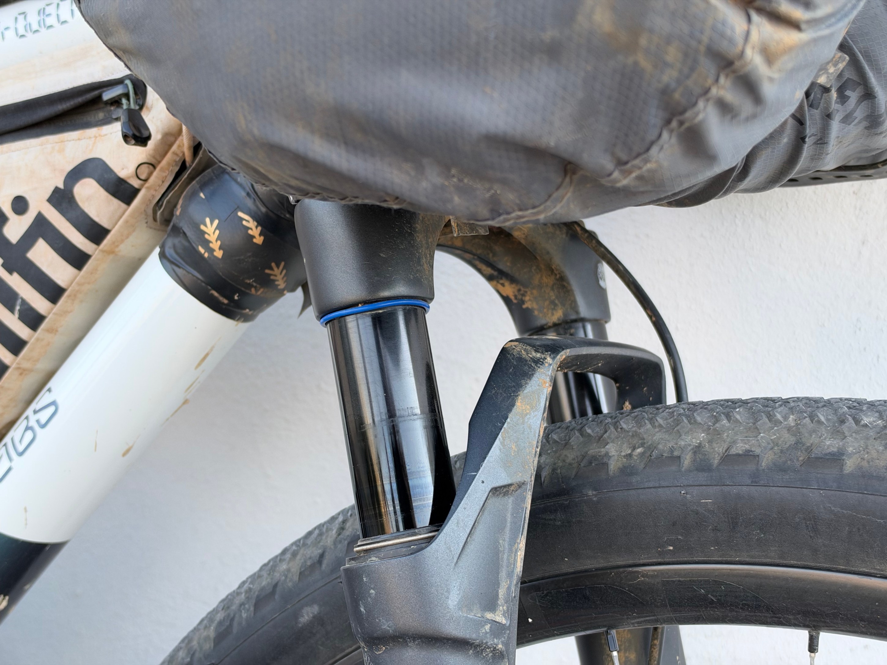 Close-up view of a bicycle's suspension fork and tire, showing dirt on the components.