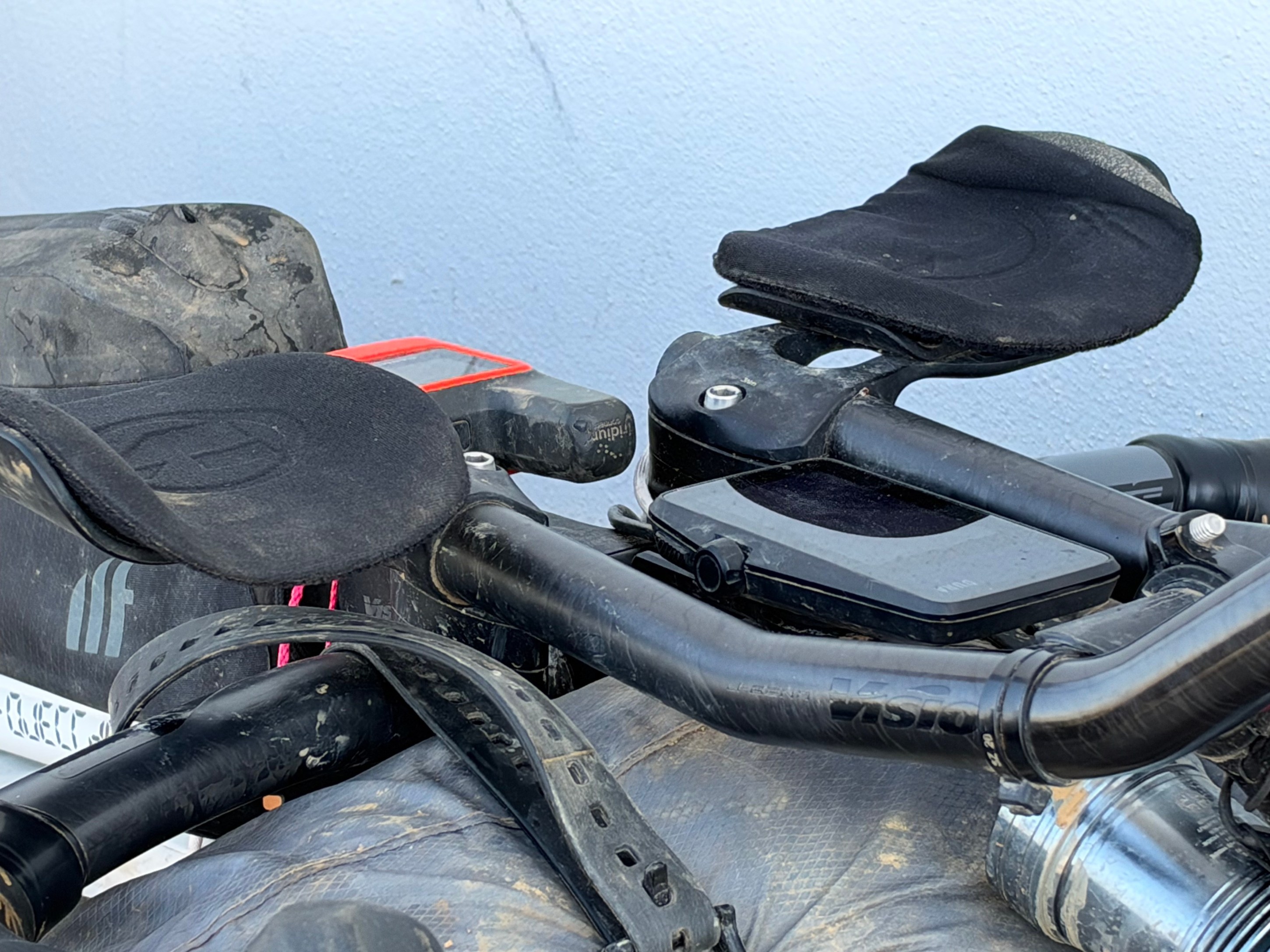Close-up view of a bicycle handlebar featuring aero bars, a computer mount, and a black saddled seat.